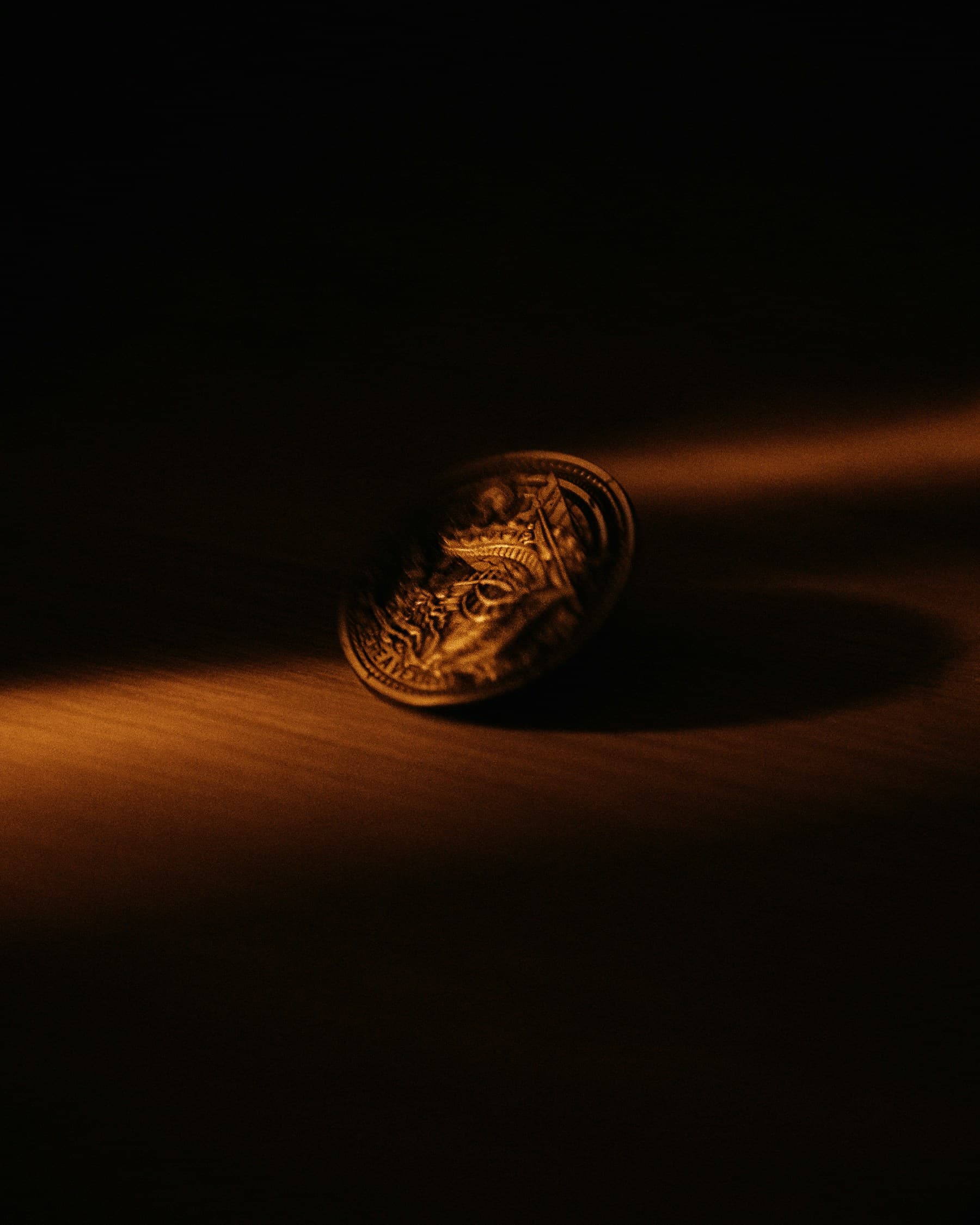 A gold coin standing on edge in a blade of warm light